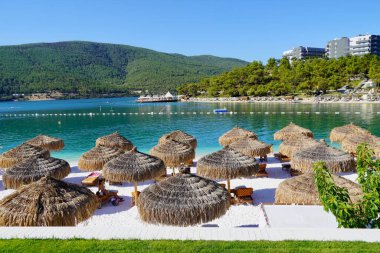 Bodrum, Türkiye - Ağustos 2020 Lux Hotel 'in kar beyazı plajı Ege Denizi' nin zümrüt suyuyla. Yatlar. İnsanlar kumsalda güneşleniyor. Kumsalda güneşli yataklar. Lüks Gebelik Rahatlatıcı. Cennet