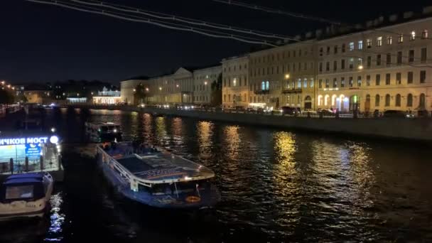 Nagranie wideo z nocy 4K pięknej podświetlanej architektury vintage nad ciemną rzeką, oświetlone ulice i budynki dużego starego portu w centrum miasta i most wyciągnąć w północnej Europie — Wideo stockowe