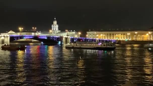 4К Знаменитый развод через мост в Санкт-Петербурге. Синие подсвеченные листья Дворцового моста, составленные медленно, темной Невы реки, много туристических лодок беспорядок вокруг, люди смотрят ночное шоу. Потрясающий пейзаж — стоковое видео