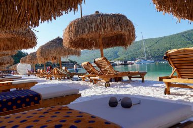Bodrum, Türkiye - Ağustos 2020 Unutulmaz deniz tatilleri için uygun plajları ve kıyıları olan Ege Denizi 'nden bir inci. Tatil afişi. Hotel Lux Lujo plajı, gün doğumunda. Bambu şemsiyeler, gök mavisi okyanus.