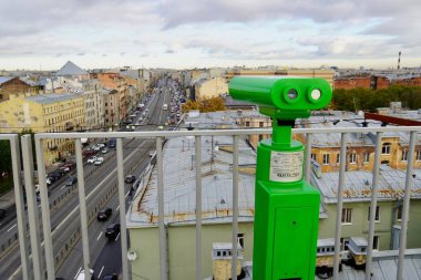 Madeni parayla çalışan yeşil dürbünler Saint-Petersburg 'un tarihi merkezinin çatısından sonbahar kentsel manzarasına bakıyor. Çatı turları