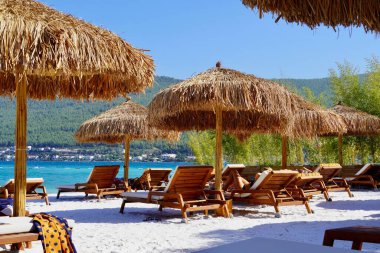 Bodrum, Türkiye - Ağustos 2020 Unutulmaz deniz tatilleri için uygun plajları ve kıyıları olan Ege Denizi 'nden bir inci. Tatil afişi. Hotel Lux Lujo plajı, gün doğumunda. Bambu şemsiyeler, gök mavisi okyanus.