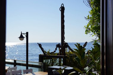 Körfez manzaralı açık bir kafe, deniz kenarındaki ahşap masa ve Marina Körfezi, Bodrum-Türkiye sahilinde açık bir kafe restoranı. Yaz tatili.