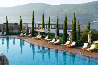  Bodrum Sahili 'nin panoramik manzarası, Ege Denizi, güneşli geleneksel otel manzarası, ince selvi, Bodrum kasabası Türkiye' de yatlar. 