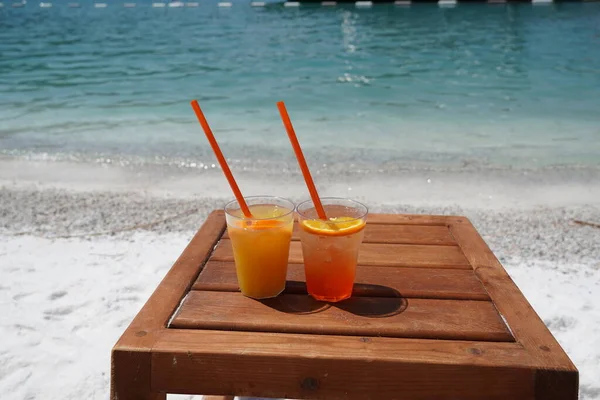Dois suco de laranja, spitz aperol na mesa de madeira na praia de areia branca com fundo barcos brancos, Amor e liberdade Relaxe Lux férias — Fotografia de Stock