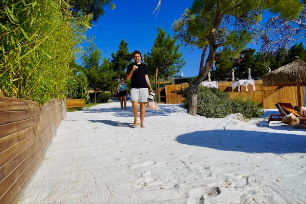 Bodrum, Turquia - Agosto de 2020 Um jovem caminha na praia branca de um hotel de luxo. Jovens em férias na ilha tropical, cara de meia idade andando na praia durante as férias na praia tropical — Fotografia de Stock