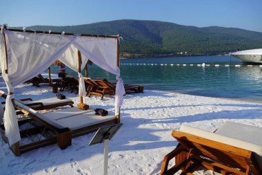 Bodrum, Türkiye - Ağustos 2020 Lujo Oteli, tropikal cennet plajı beyaz kum ve kakao palmiyeleri ile tüm panorama arka planında seyahat ediyor. Lüks tatil ve tatil afişi, tropik sahil beldesi