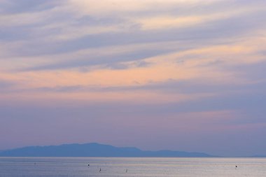 Serene seascape with pastel sky and distant mountains.