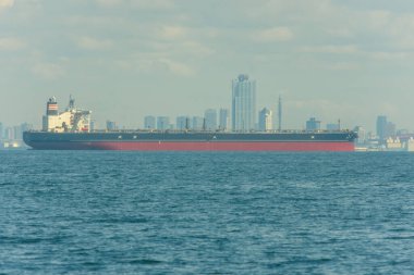 Büyük bir kargo gemisi 8 Ekim 2017 'de Japonya' nın Osaka şehrinde arka planda bir Osaka şehrinin silueti ile okyanusta yol alıyor.