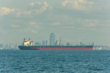 Büyük bir kargo gemisi 8 Ekim 2017 'de Japonya' nın Osaka şehrinde arka planda bir Osaka şehrinin silueti ile okyanusta yol alıyor.