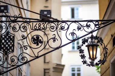 Ornate wrought iron sign with a lantern and the year 1683.