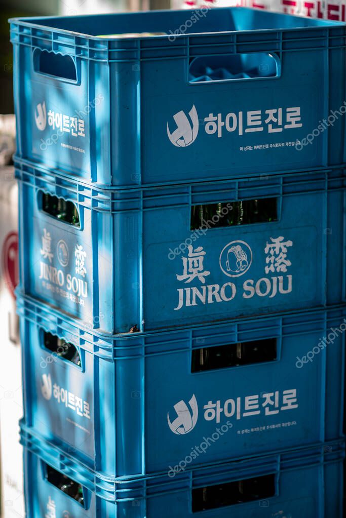 Stacked blue crates of Jinro Soju bottles in sunlight outside a store in Seoul, South Korea on 12 November 2023