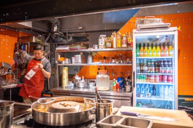 Seul, Güney Kore 'de 27 Ekim 2023' te çeşitli baharatlarla çevrili bir aşçı ve içkilerle dolu bir buzdolabı ile dolu bir mutfak.