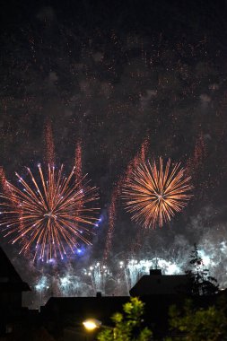 Siluetli binaların üzerinde gece gökyüzünde renkli havai fişekler patlıyor..