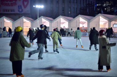 İnsanlar 29 Ocak 2024 'te Güney Kore' nin Seul kentindeki belediye binasının önündeki geçici buz pateni pistinde buz pateni yapıyorlar.
