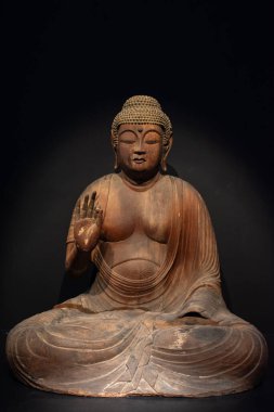 Tahta Buda heykeli, meditasyon pozisyonu almış ve elini kaldırmış.