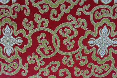 Karmaşık çiçek desenleriyle süslü kırmızı ve altın kumaş..