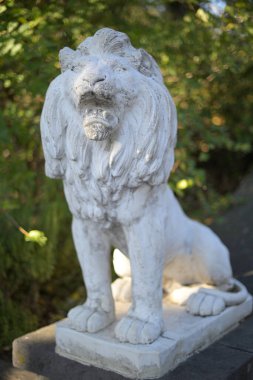 Yeşillik arkaplanı olan taş bir aslan heykelinin yakın çekimi