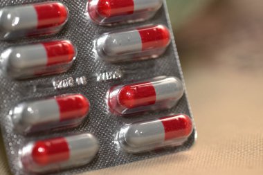 Bej bir yüzey üzerinde kırmızı ve gri kapsüllü kabarcık paketi.