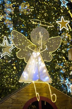 Aydınlatılmış melek süslemesi Kanatlı ve haleli Noel ağacında.