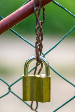 Pirinç bir asma kilit tel bir çitte zincir emniyete alıyor..