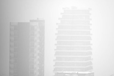 Yüksek binaları zar zor görünen sisli şehir manzarası.