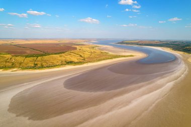 Yeşil ve sarı tarlalarla çevrili açık bej renkli kurutulmuş tuzlu gölün inanılmaz güzelliği. Yazın parlak bir tuz deposunun havadan görünüşü. Vuruldu. Kurutma haliçinin kuş bakışı görüntüsü
