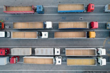Birçok kamyon limanda boşaltma kuyruğunda bekliyor, tahıl yüklü kamyonlarla bir kuadkopterin üst görüntüsü. Lojistik ve nakliye kavramı.