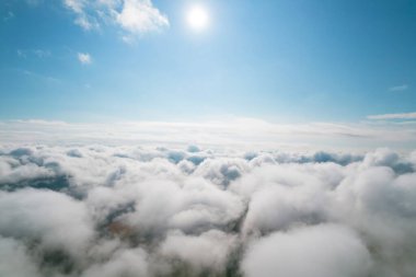 Kümülüs bulutları, hava arkaplanı. Beyaz kabarık bulutların üst görüntüsüyle hava görüntüsü. Bulutların arasında zemin burada ve orada görünür.. 
