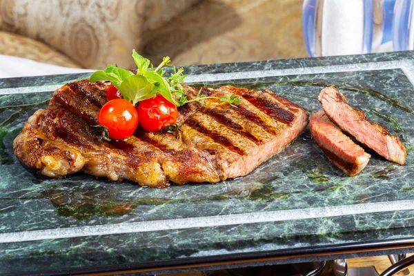 Carne grelhada com tomates em uma bandeja de mármore — Fotografia de Stock