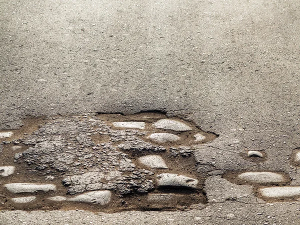 Cutting of an old road with cracked asphalt and a gully in the c — Stock Photo, Image