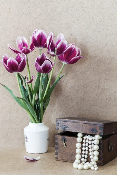 Fleurs violettes lumineuses dans un vase blanc tulipes et poitrine en bois wi — Photo