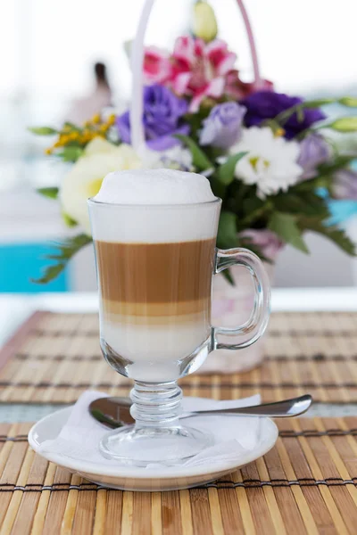 Latte in a glass with a blurred background of a beautiful bouque — Stock Photo, Image