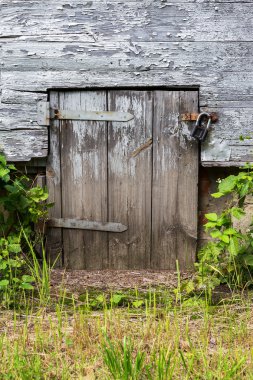 Old wooden door closed on the lock. Rural landscape.