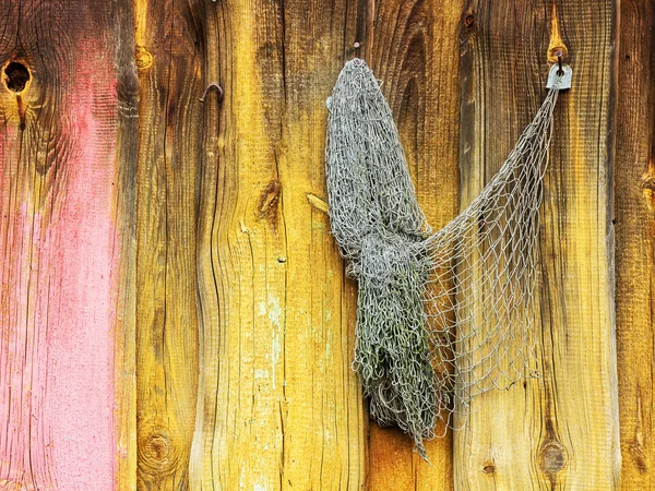 Old fishing nets hang on the painted wooden wall of a barn — ストック写真