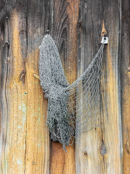 Old fishing nets hang on the painted wooden wall of a barn — ストック写真