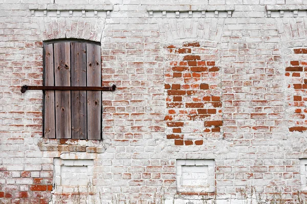 Old window with creative metal bars on the white stone wall — Stock Photo, Image