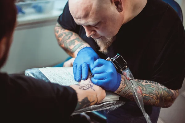 Maestro tatuador hace un tatuaje en la piel — Foto de Stock