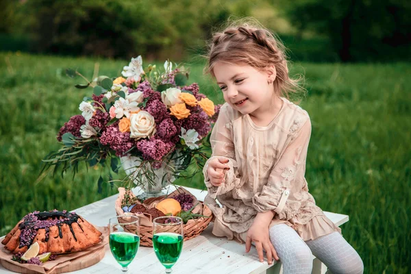 Little baby girl eats chocolate cake in nature at a picnic — Stock Photo, Image