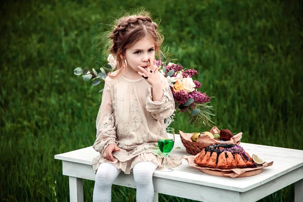 Little baby girl eats chocolate cake in nature at a picnic — Stock Photo, Image