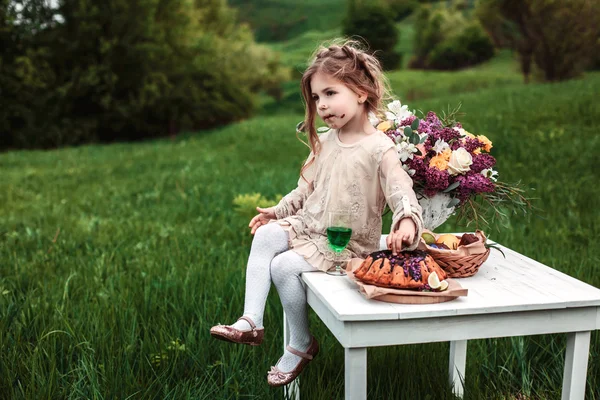 Little baby girl eats chocolate cake in nature at a picnic — Stock Photo, Image