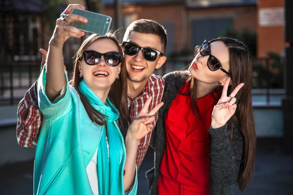 two young women and the guy taking selfie with mobile phone