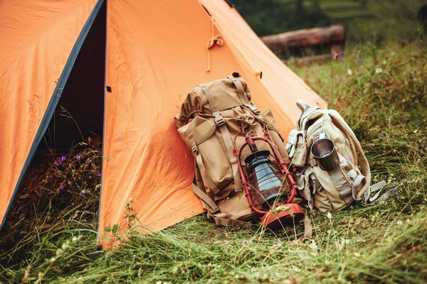 Das Zelt und zwei Rucksäcke in der Nähe einer Touristenpiste in den Bergen auf grünem Gras — Stockfoto