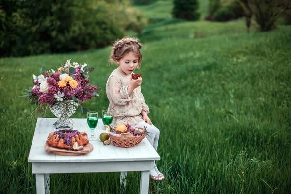 Little baby girl eats chocolate cake in nature at a picnic. — Stock Photo, Image