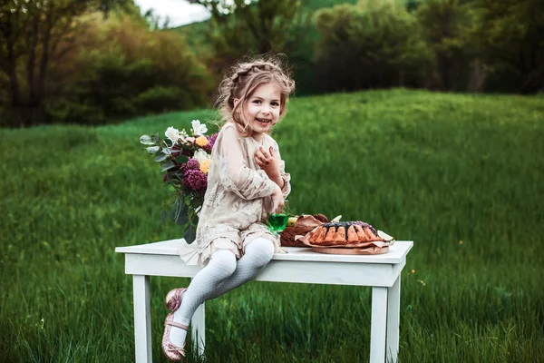 Bambina mangia torta al cioccolato in natura a un picnic . — Foto Stock