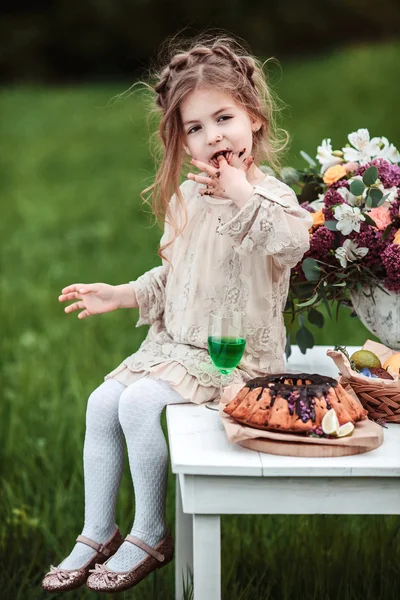 Mała dziewczynka zjada ciastko czekolada w przyrodzie na pikniku. — Zdjęcie stockowe