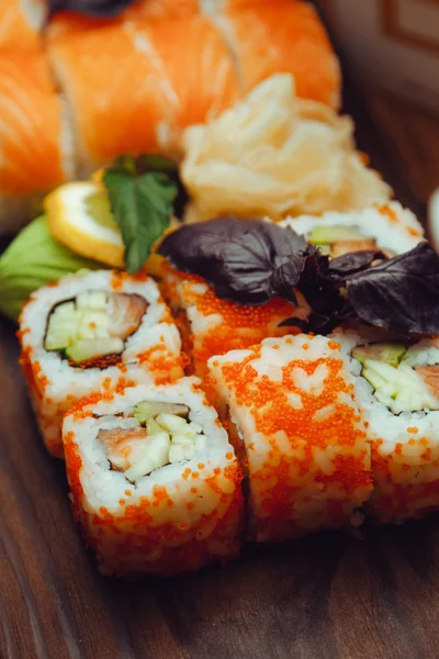 Bela comida chinesa e rolos de sushi em fundo de madeira — Fotografia de Stock