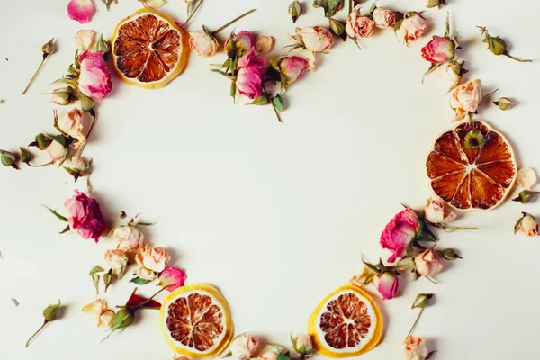 Beau fond avec des roses et des fleurs séchées tranches rondes de citron séchées posées sur un fond blanc — Photo