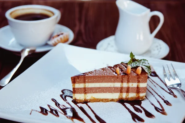 Rebanada de pastel de queso con chocolate derretido en plato blanco y café — Foto de Stock