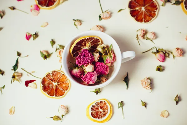 dried flowers dried roses and round slices of lemon laid on a white background and the white Cup